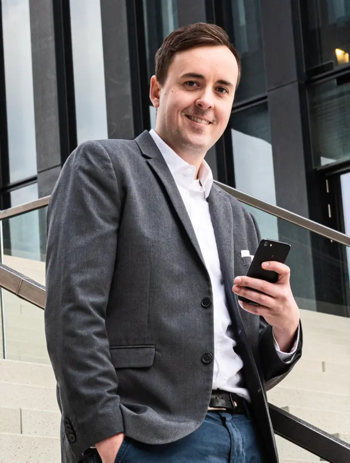 Man in blazer holding a smartphone